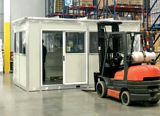 an portable office with electricity, lights, and space for working within a larger warehouse building
